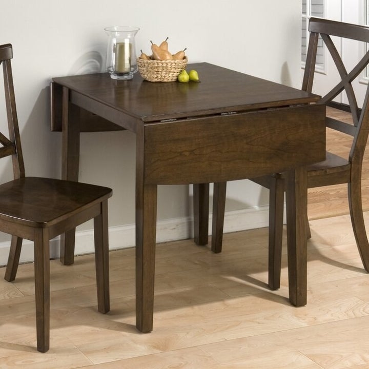 wood dining table with drop leaves down and against a wall