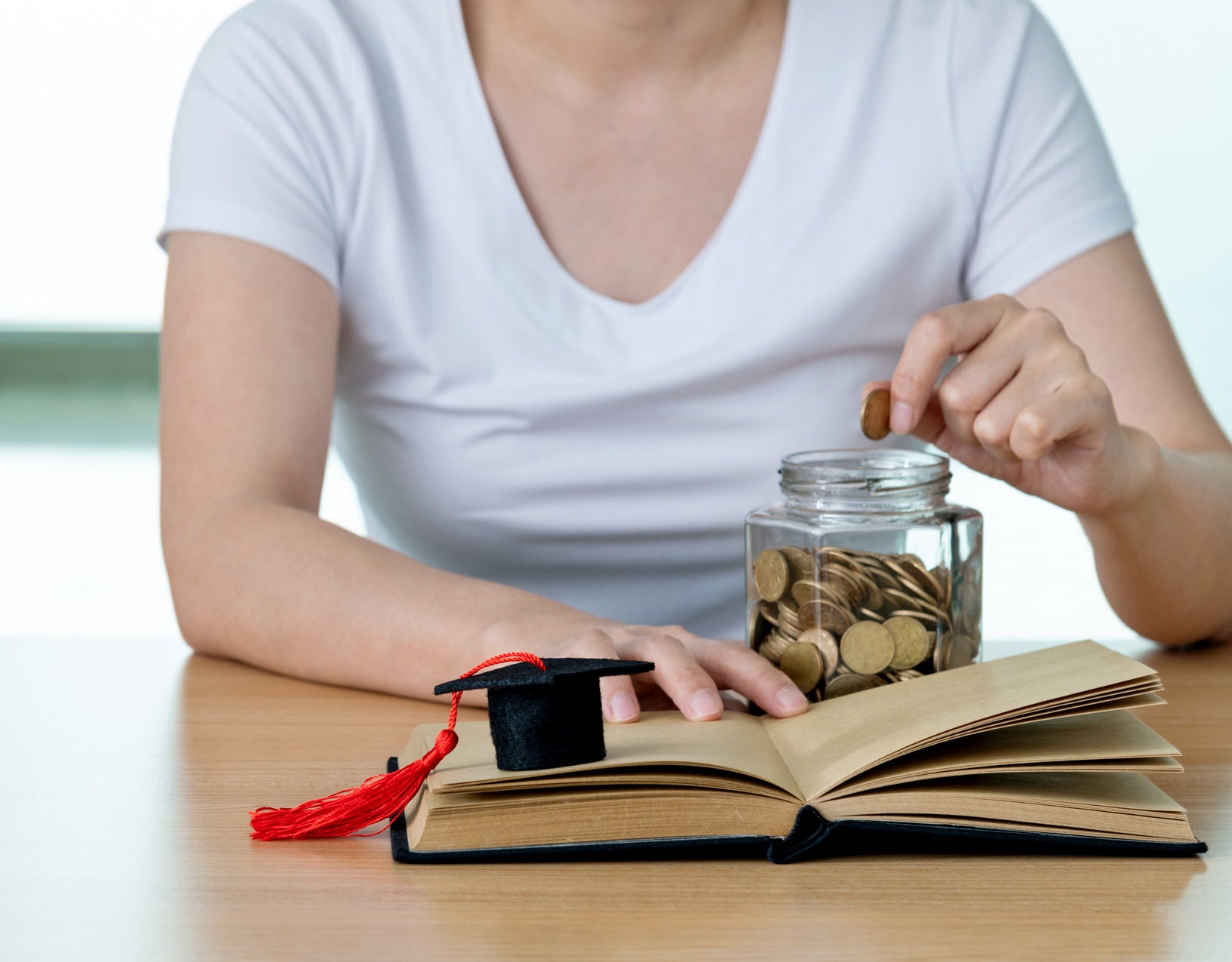 A person putting money into a jar for college
