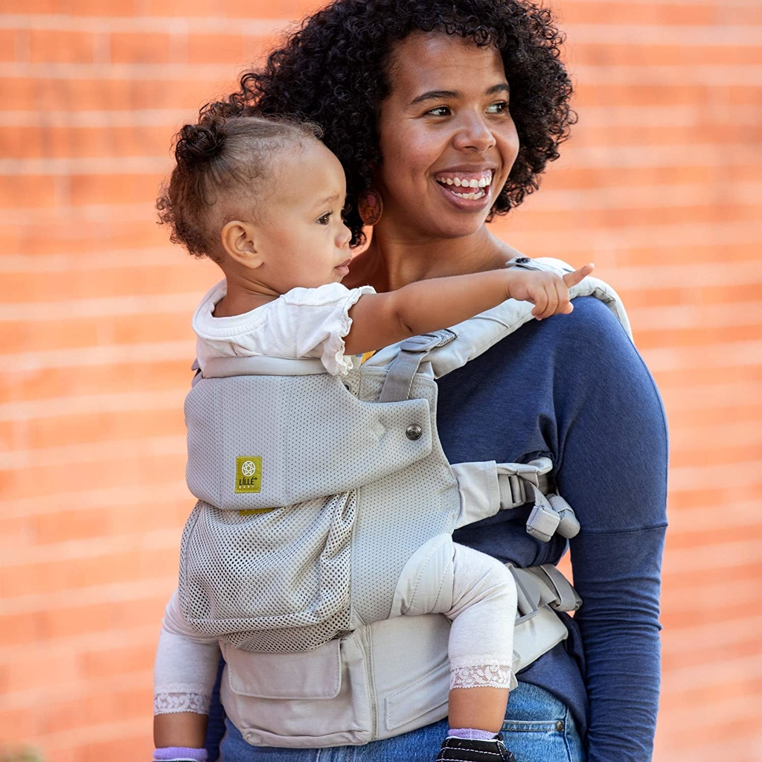 Adult model carrying a child in a light gray child carrier 