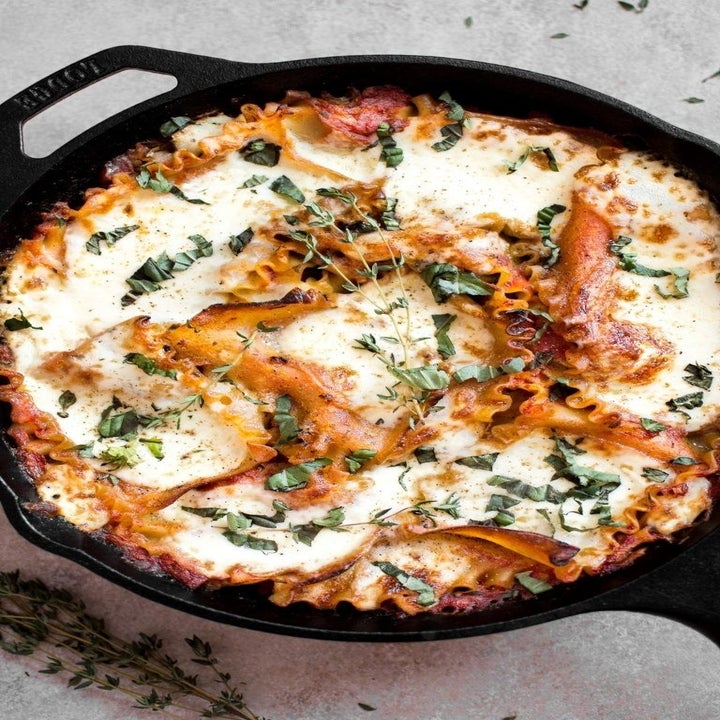 A cast iron skillet filled with super cheesy lasagna.