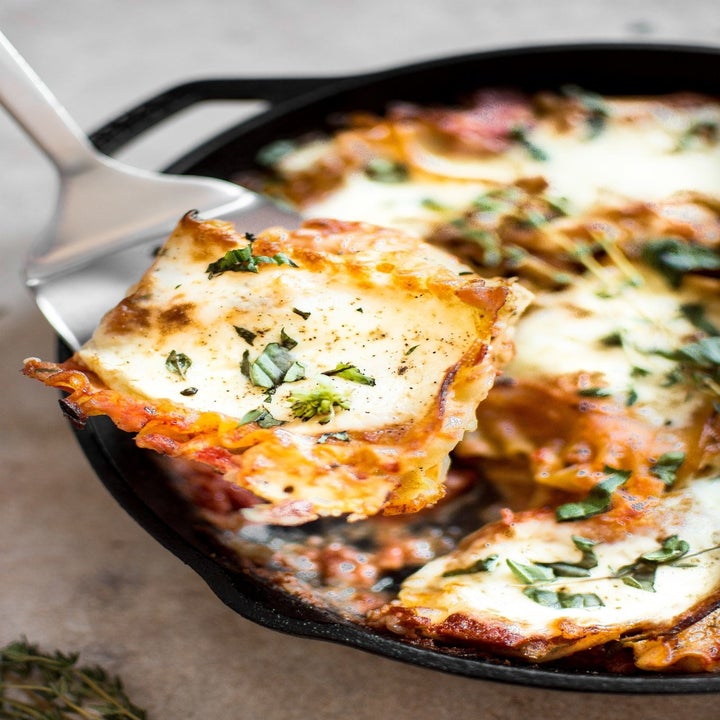 A spatula lifting up a slice of cheesy Caprese skillet lasagna.