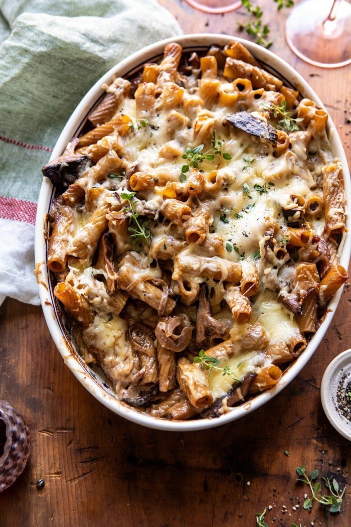 A baking dish filled with penne topped with caramelized onions and melted Gruyère cheese.