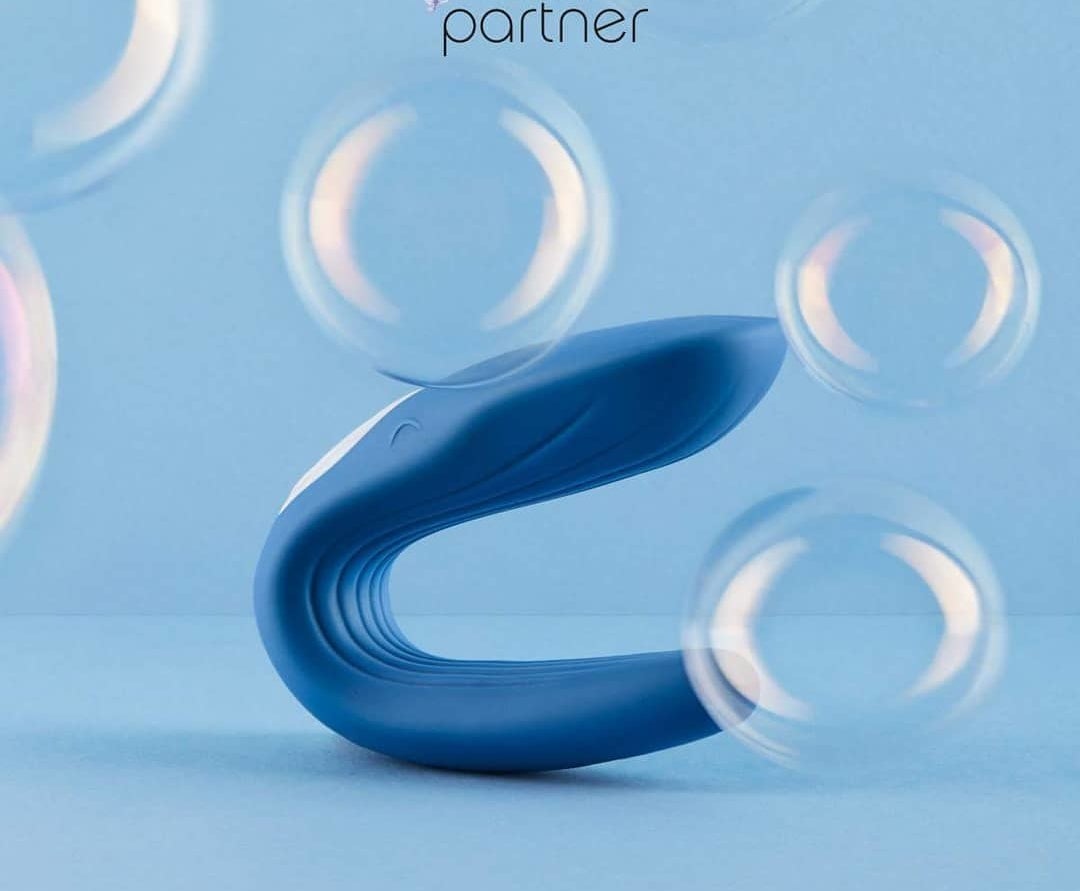 The blue Satisfyer Partner Double Whale displayed against a blue backdrop with bubbles