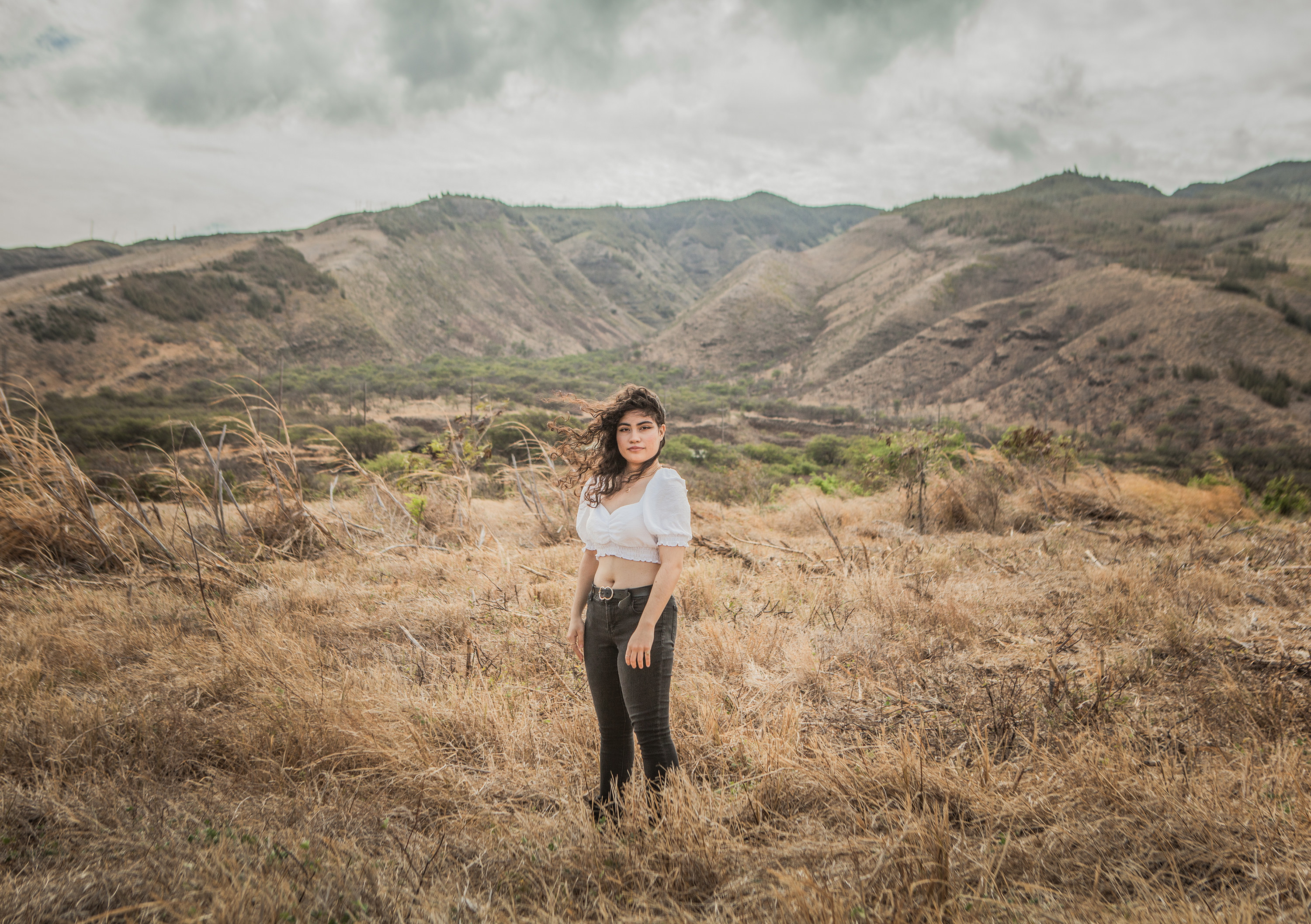 A young woman in a crop top in a hilly landscape