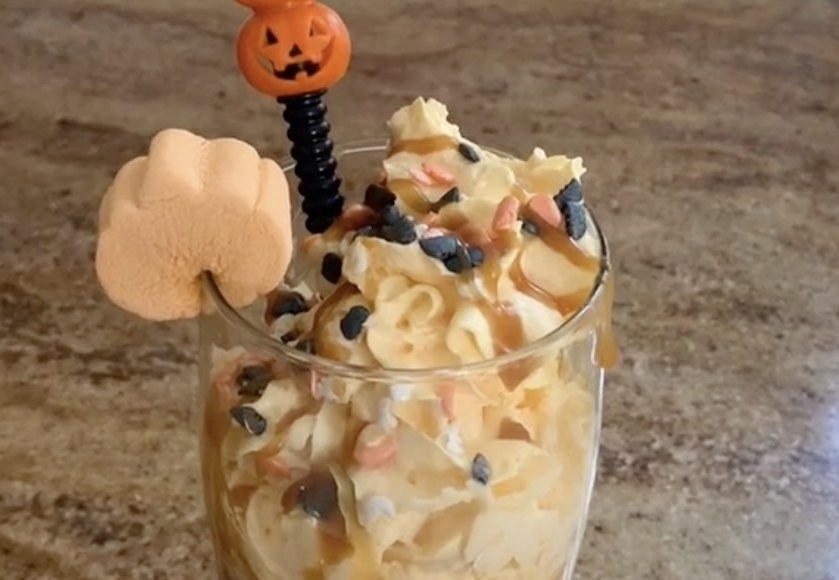 A coffee drink with lots of orange whipped cream and sprinkles 