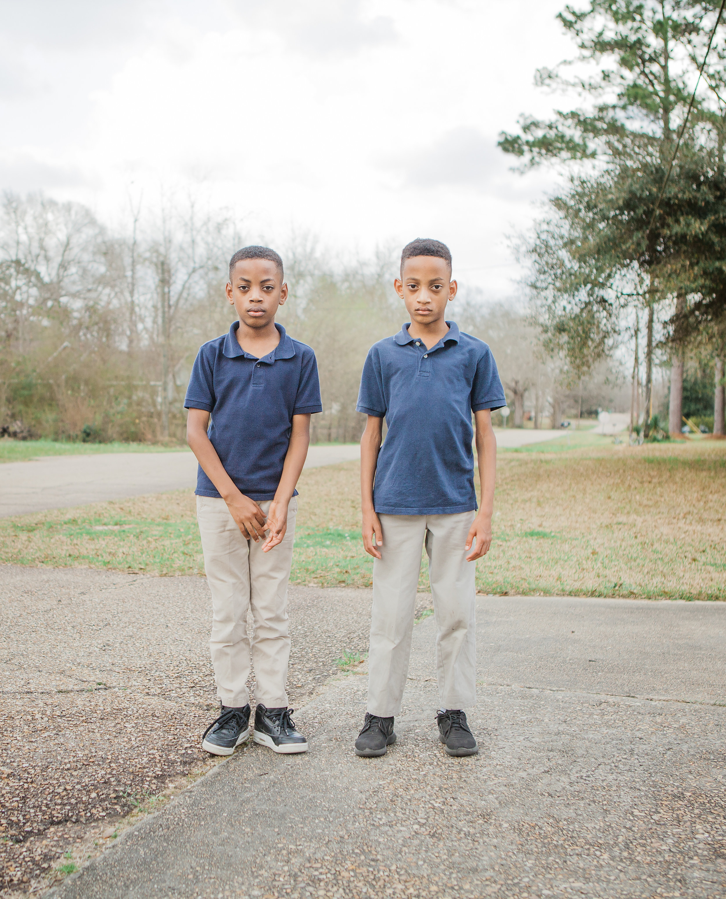 Two young boys in school uniforms on a sidewalk 