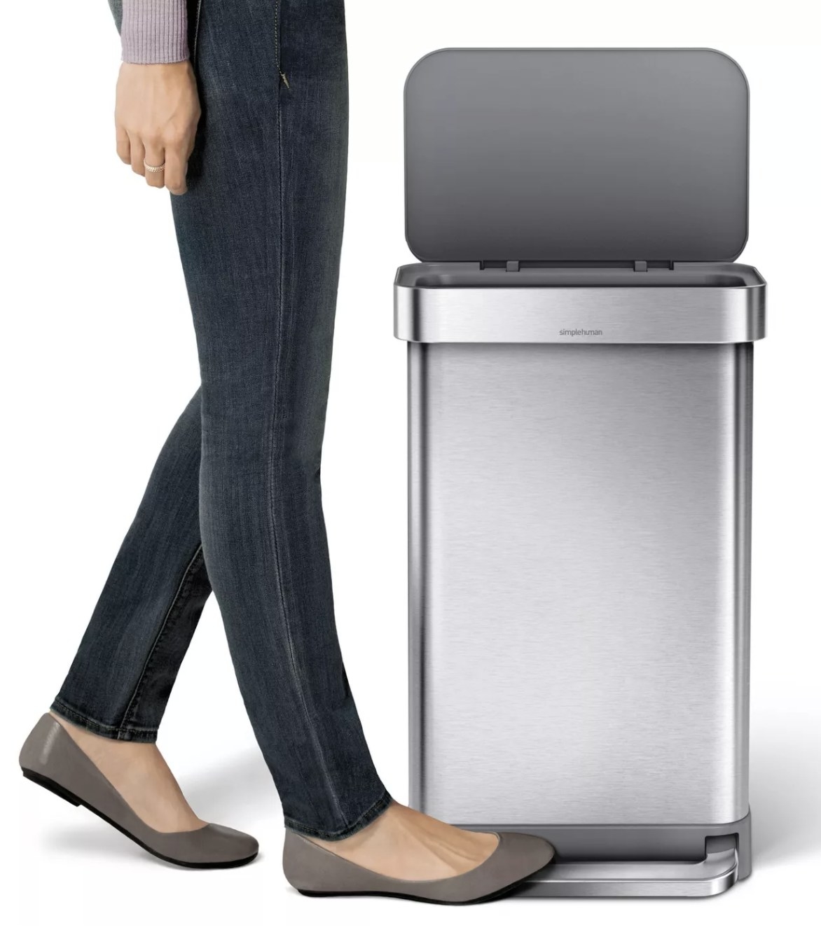 a person stepping on a silver trashcan&#x27;s base to open the lid