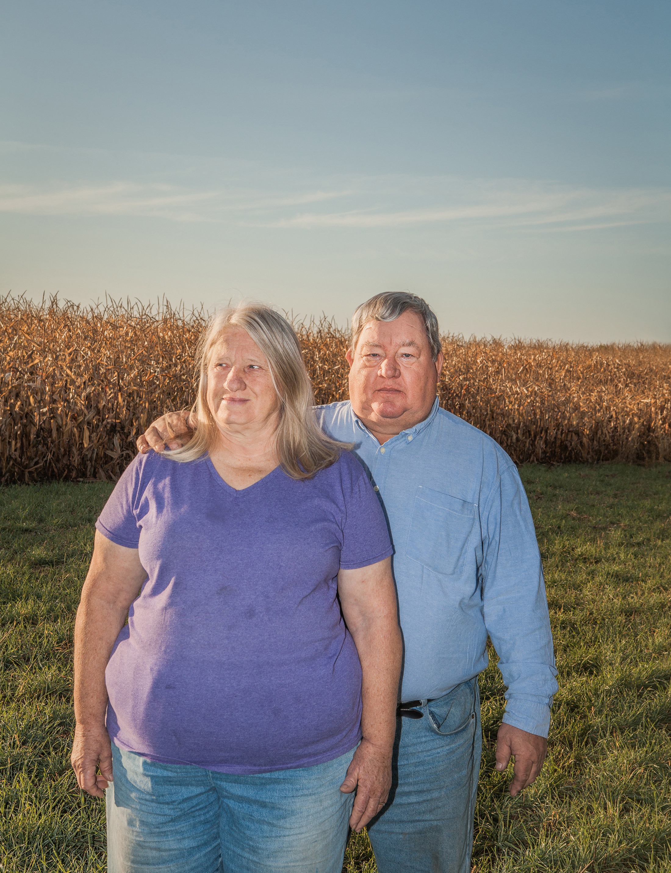 An older couple in jeans in a corn field 