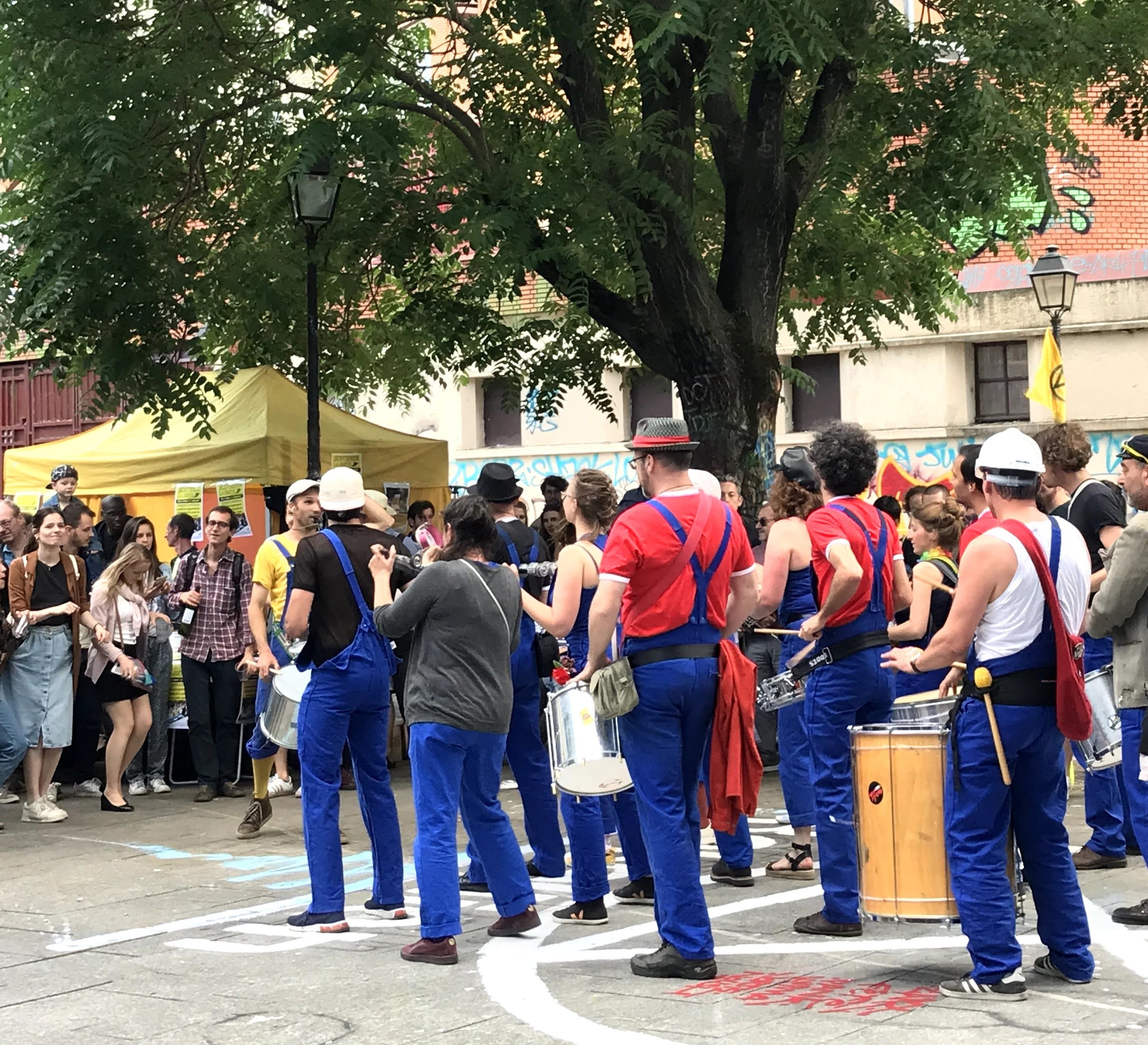 Group of musicians stand on the sidewalk playing music for an audience