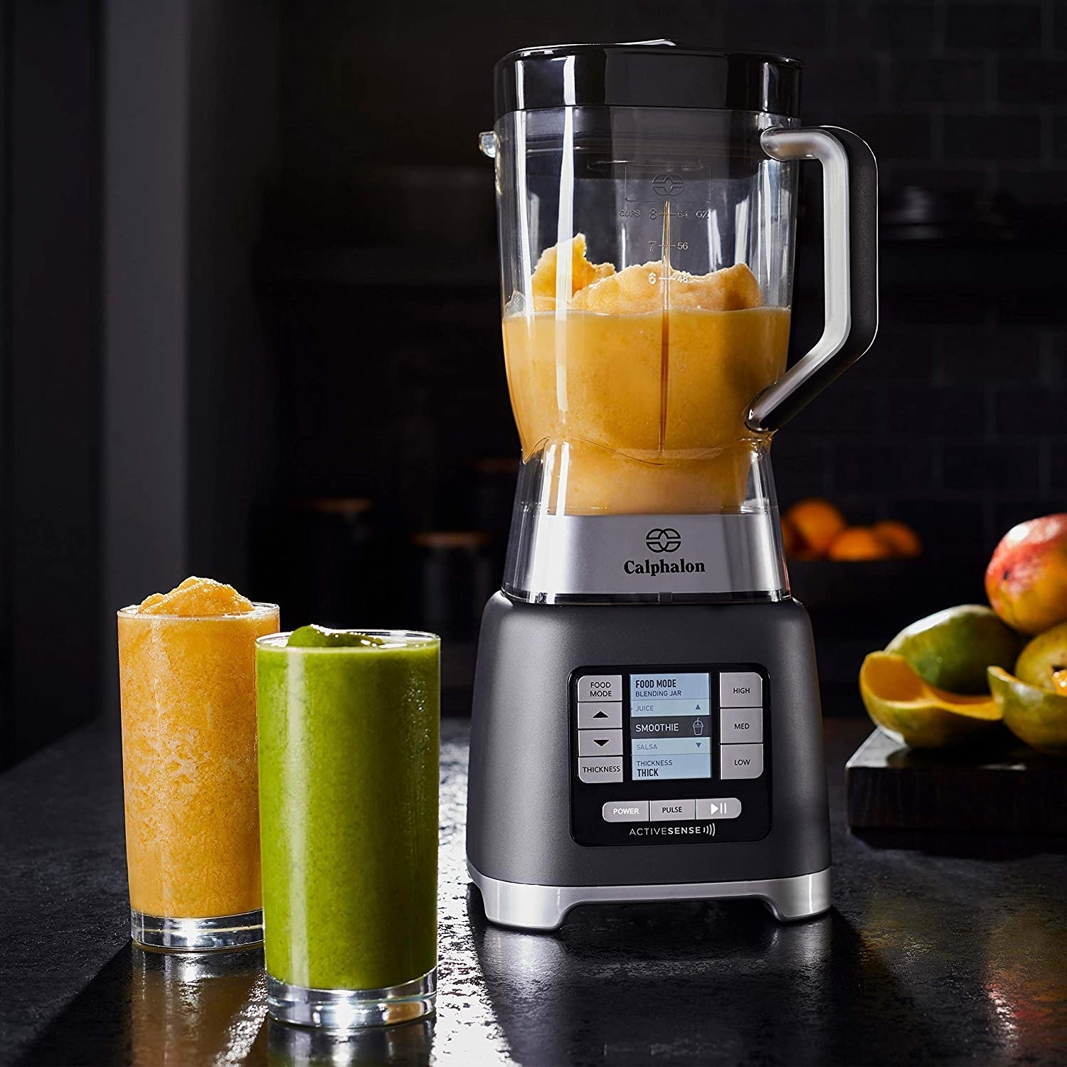 A blender filled with a smoothie with two glasses of smoothie next to it