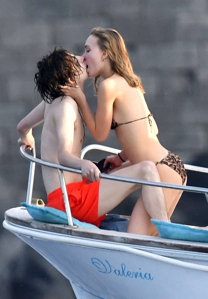 Timothée and Lily awkwardly kissing on the deck of a boat 