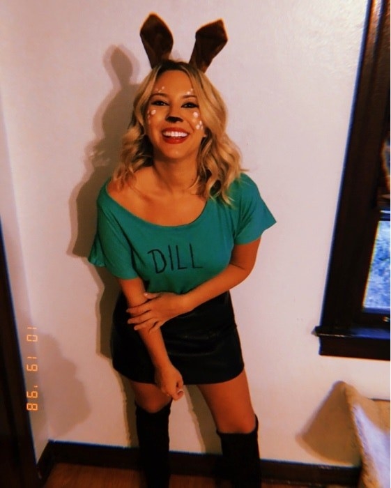 A woman with deer face paint and ears, and a green shirt that says &quot;dill&quot;