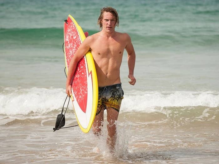 A man holding a surfboard and jogging out of the water