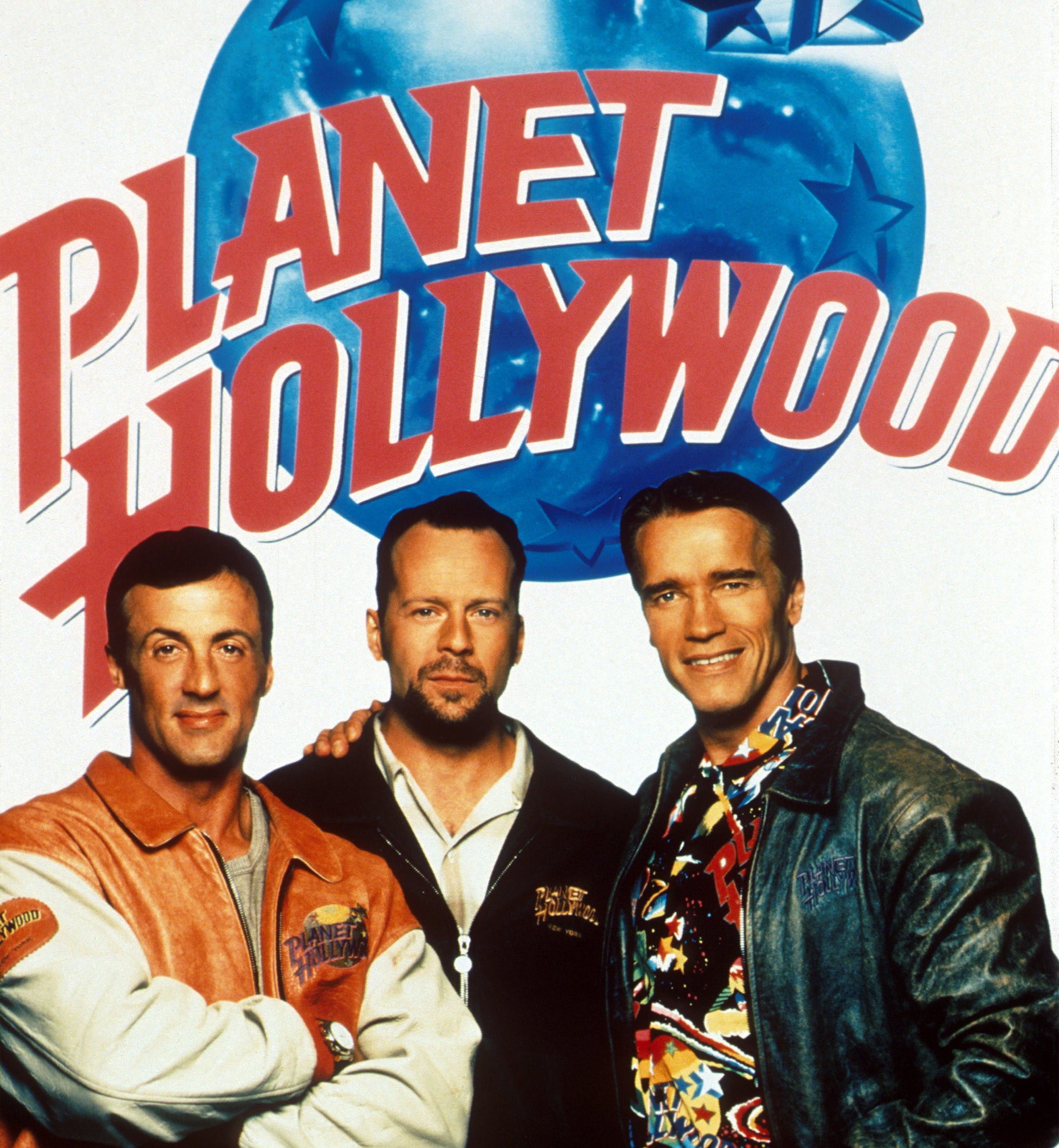 A poster for Planet Hollywood featuring Sylvester Stallone, Bruce Willis, and Arnold Schwarzenegger