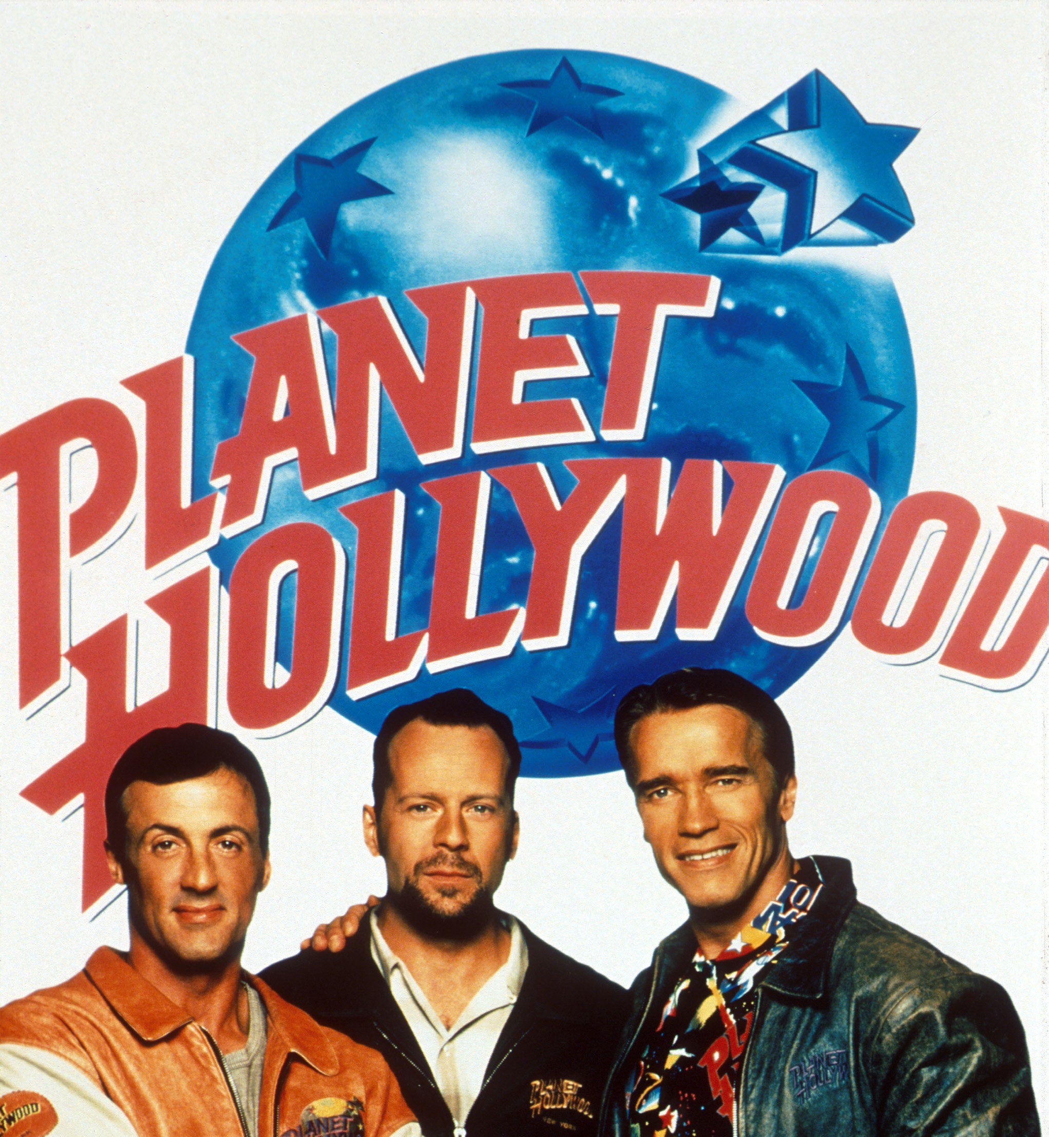 A poster for Planet Hollywood featuring Sylvester Stallone, Bruce Willis, and Arnold Schwarzenegger