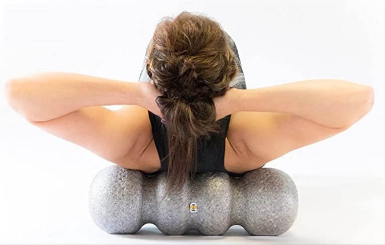 A woman using a foam roller with grooves