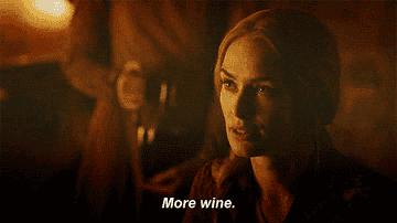 Cersei Lannister in &quot;Game of Thrones&quot; holding up her glass asking for more wine.