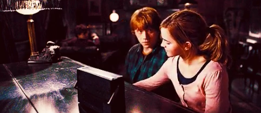 Ron staring at Hermione while they play piano together