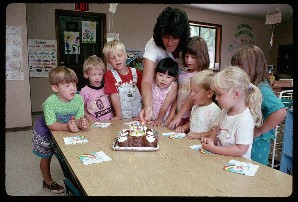 Preschoolers watching a birthday cake being lit by the teacher in the early &#x27;90s