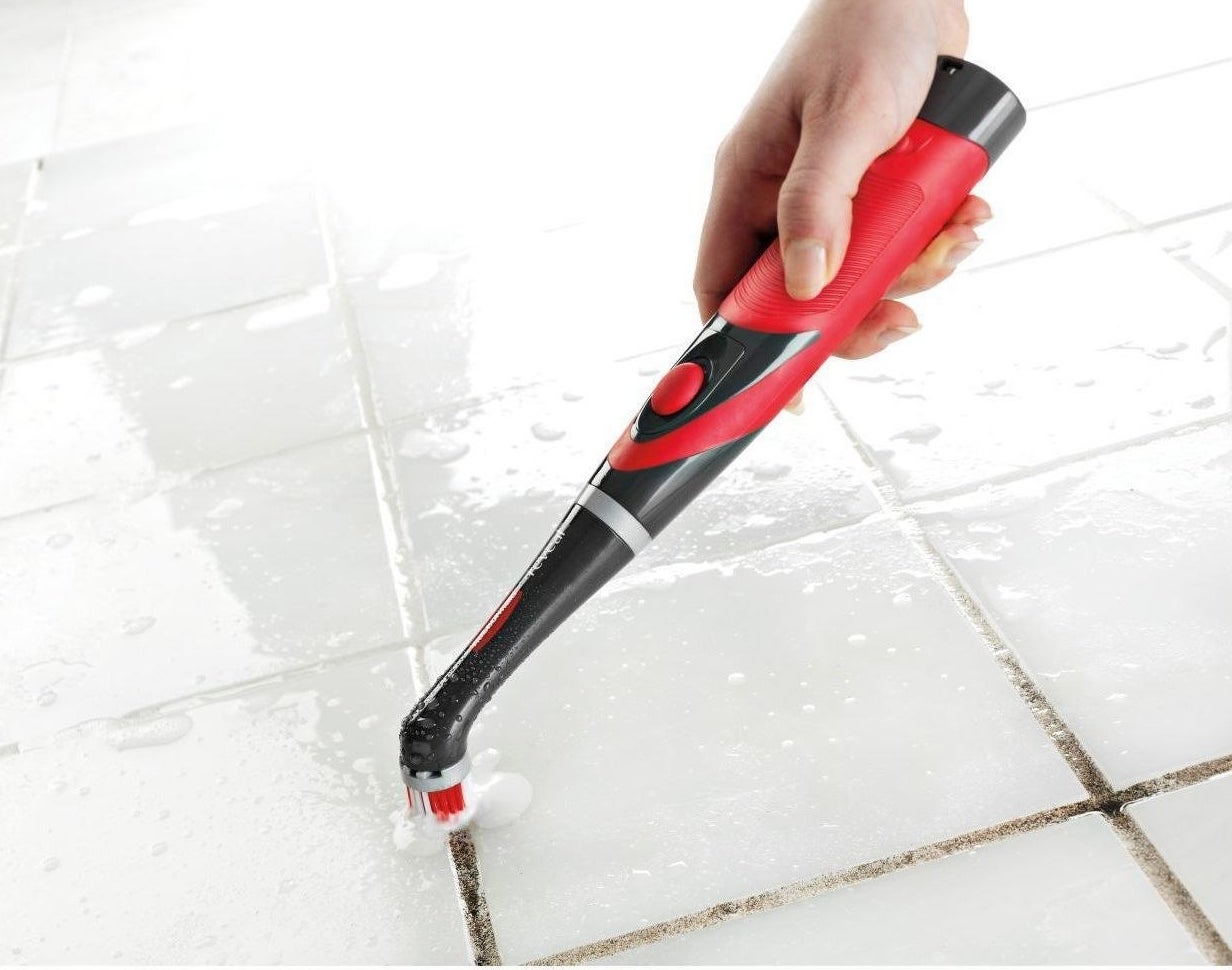 Red and black scrubber cleaning grout