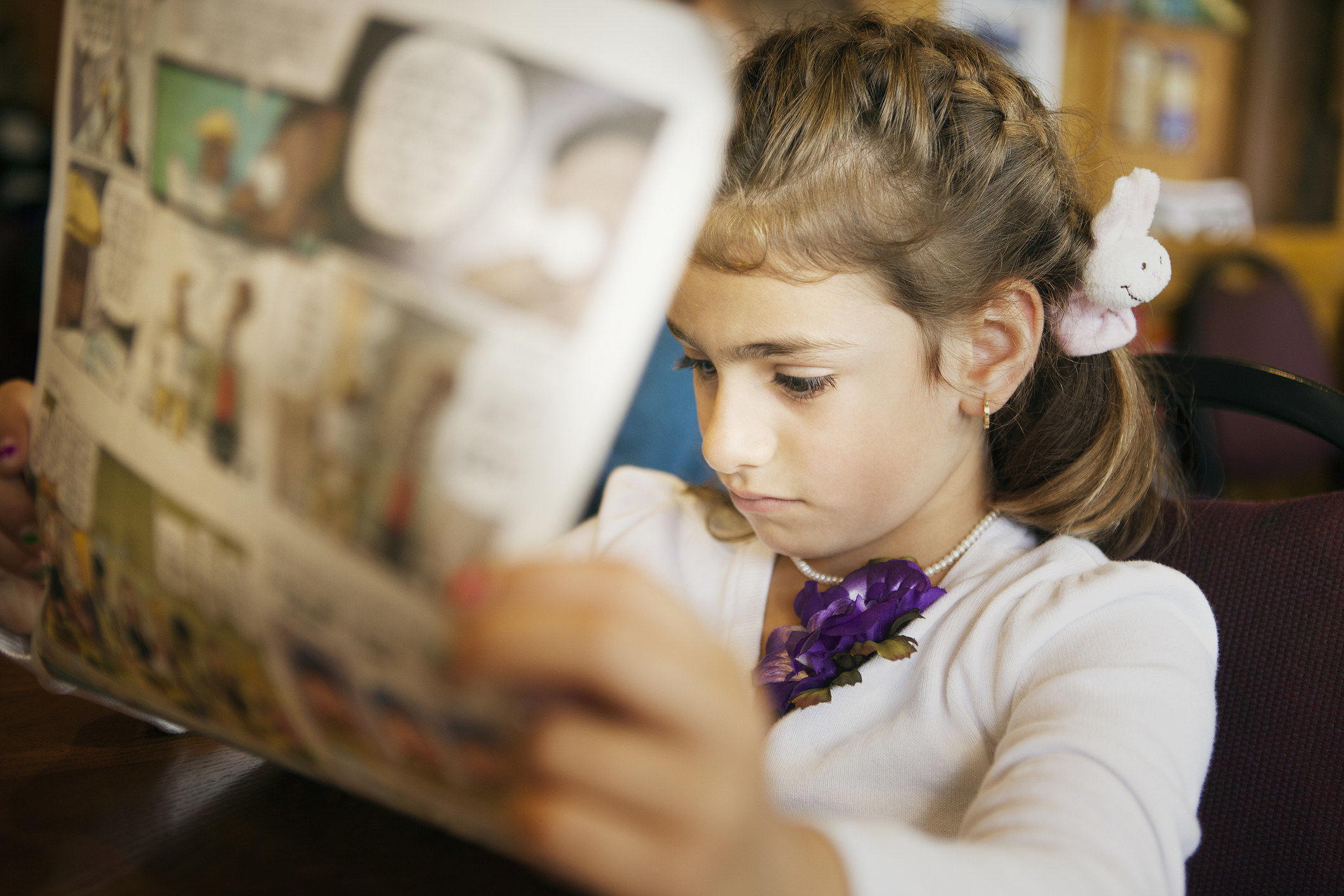 A stock image of a little girl reading the Sunday comics