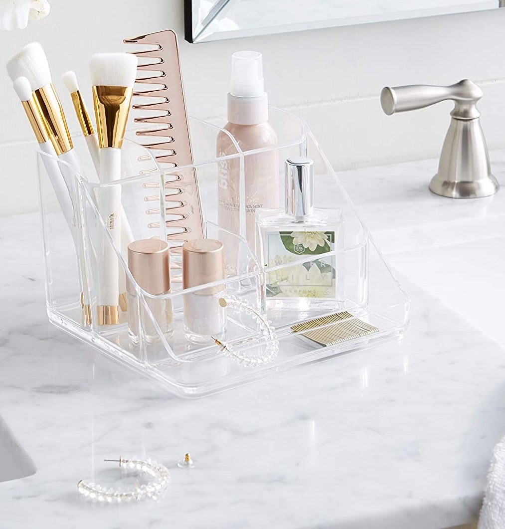 Several brushes, beauty products, and pieces of jewelry inside of the organizer