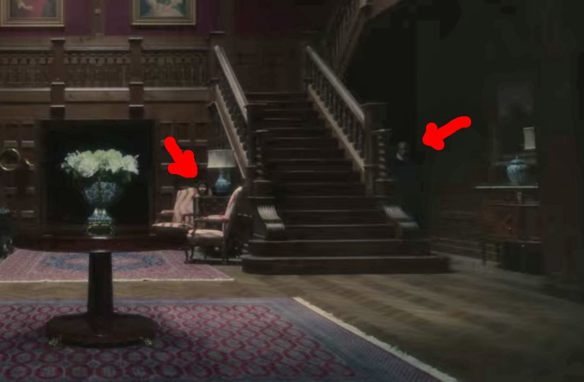 The foyer of Bly Manor with red arrows pointing to the ghost boy and a pale man on either side of the staircase