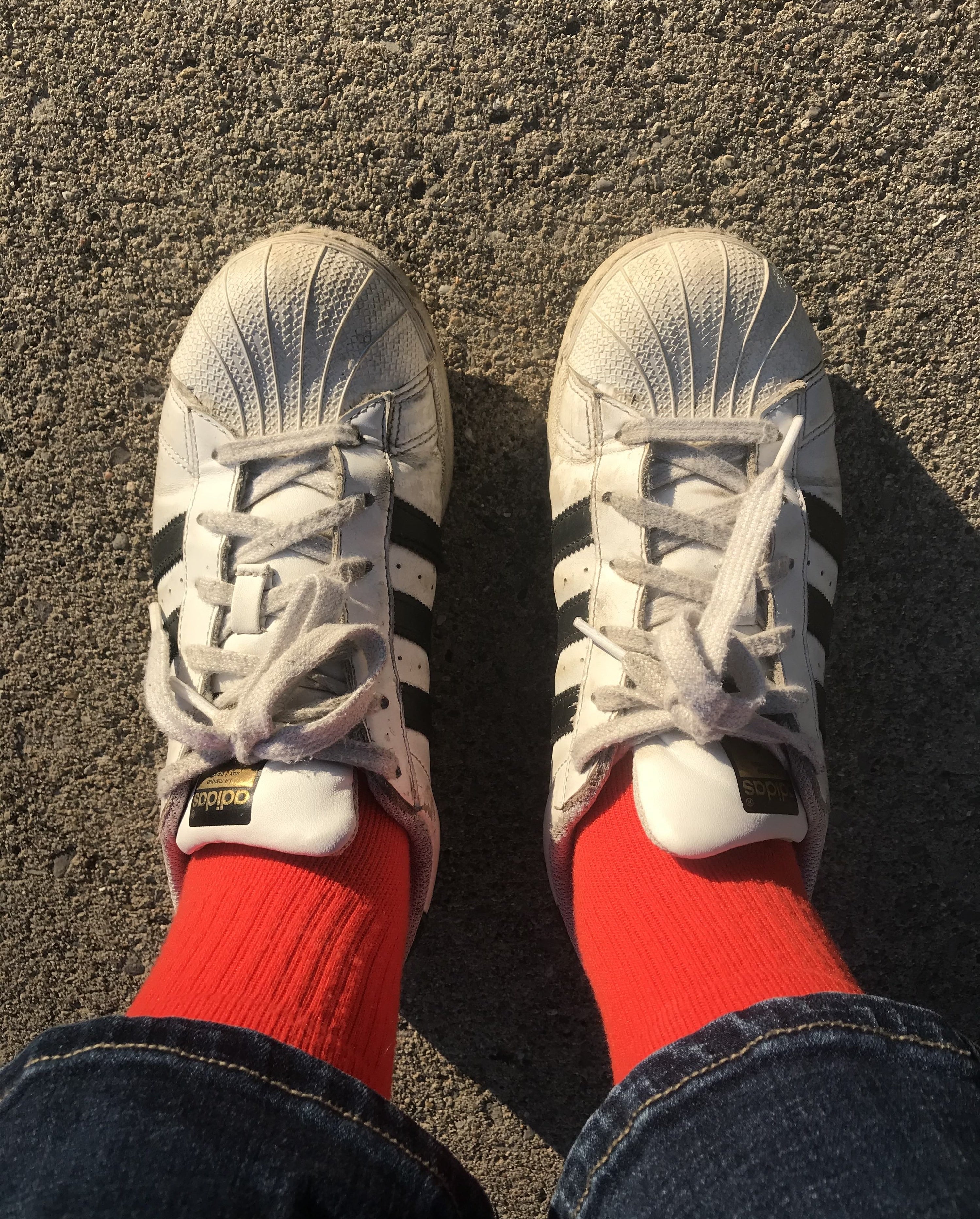 writer wearing worn black and white adidas sneakers