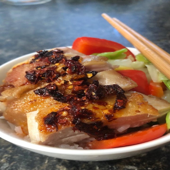 Sliced chicken on a salad topped with the spicy chili crisp hot sauce.