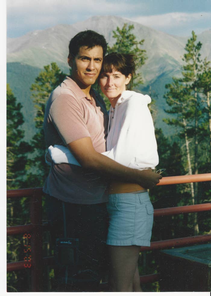 Rey River and his wife, Allison, stand outside in front of a gate by trees and a mountain