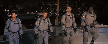 The ghostbusters walk in a line, pulling out their guns