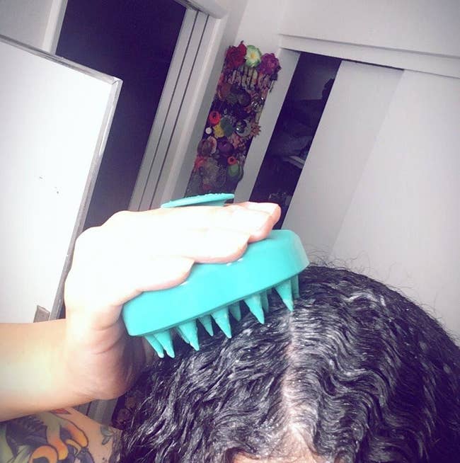 A reviewer using the teal silicone brush on their wet, shampooed hair