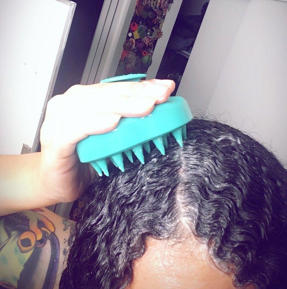 A reviewer using the teal silicone brush on their wet, shampooed hair