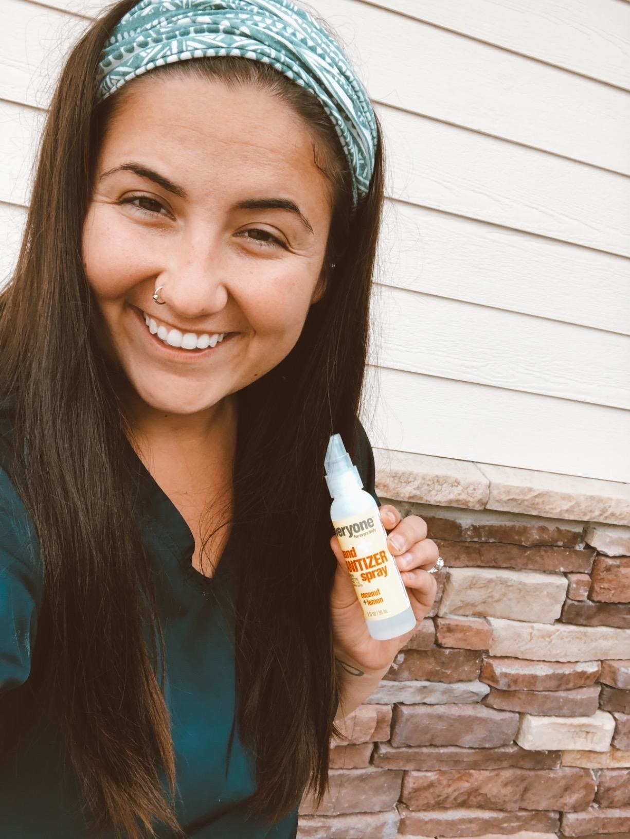 A happy customer holding a bottle of the Everyone Hand Sanitizer Spray