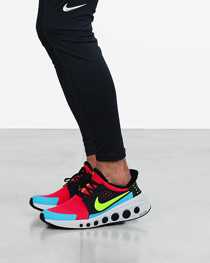 Model wears blue, red, and neon green Nike CruzrOne unisex running shoes