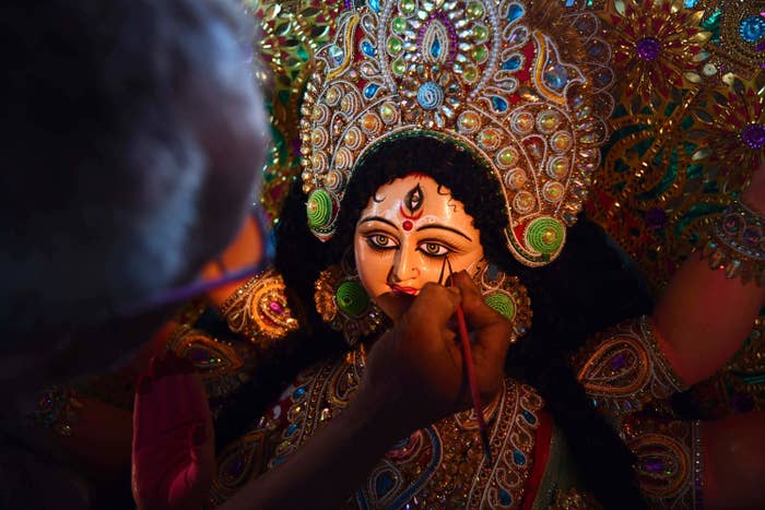 An artisan gives finishing touches to an idol of goddess durga