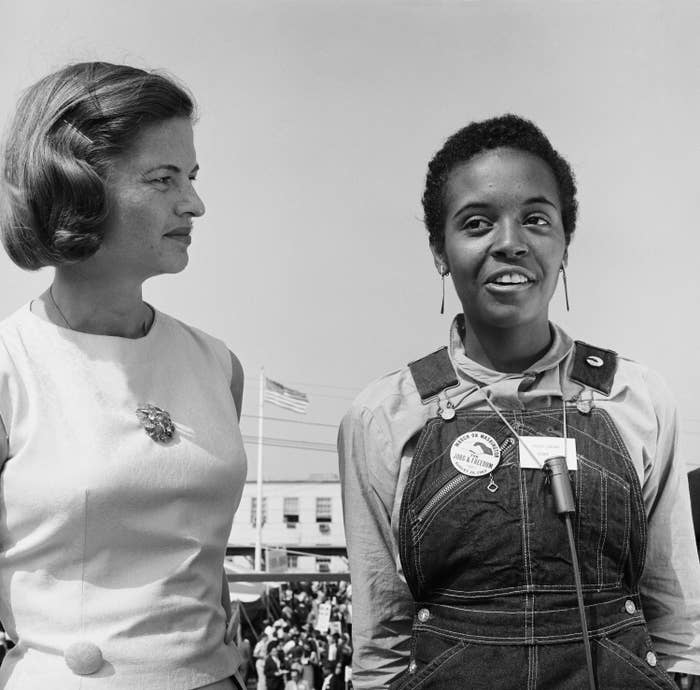 A Black woman, wearing a March on Washington pin, and a white woman stand side by side