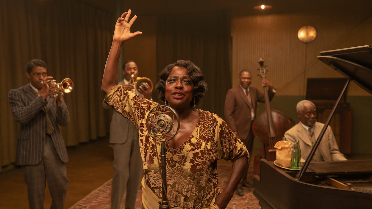 Viola Davis singing at a microphone with a band behind her 