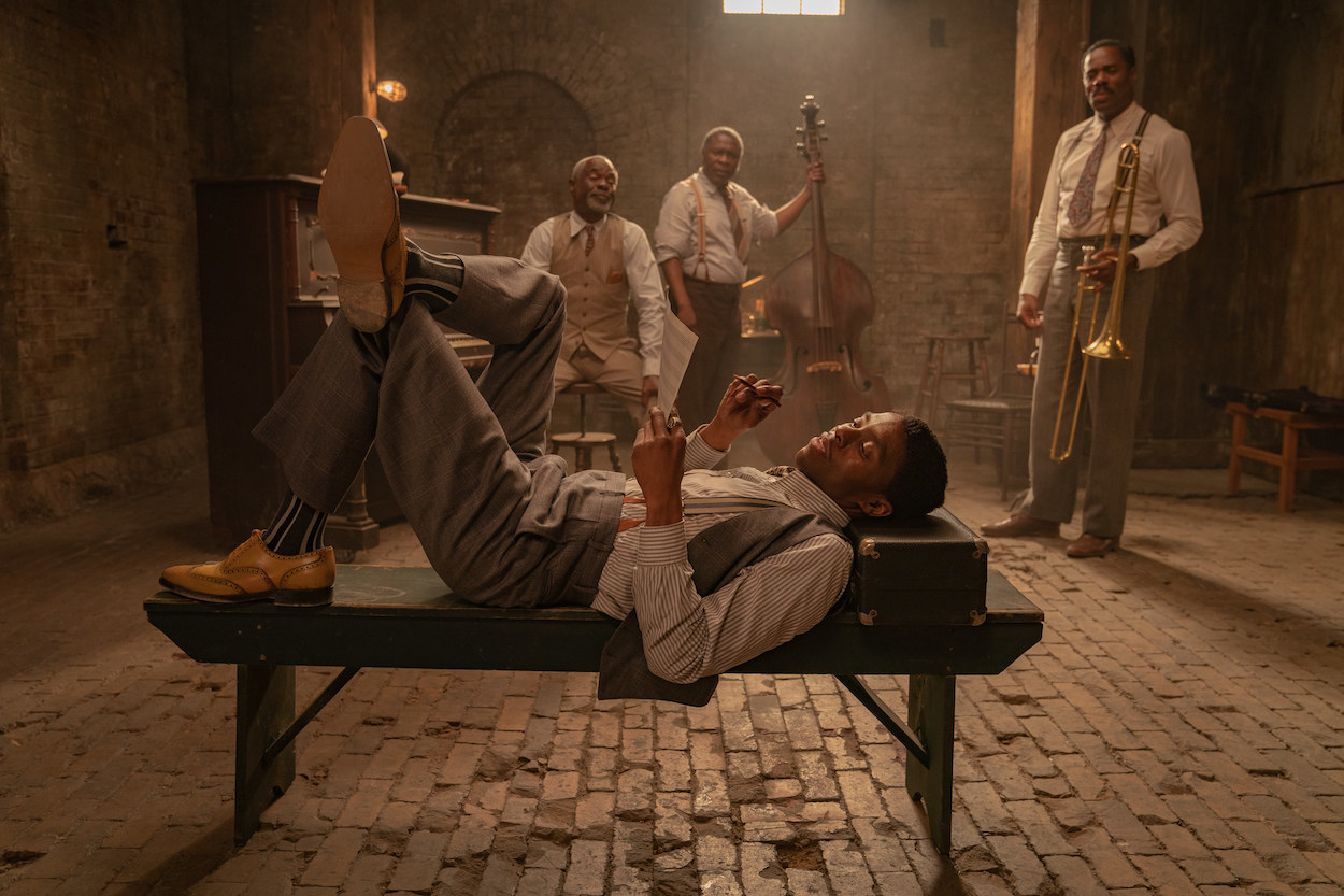 Chadwick lying on a bench in a basement while men with instruments stand in the background 