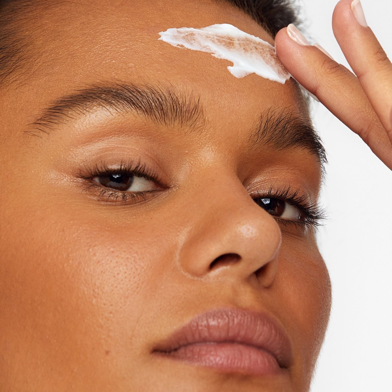 A model applying the white cream to their forehead