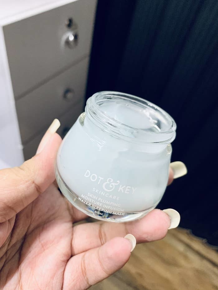 A hand holding an open bottle of the cream.