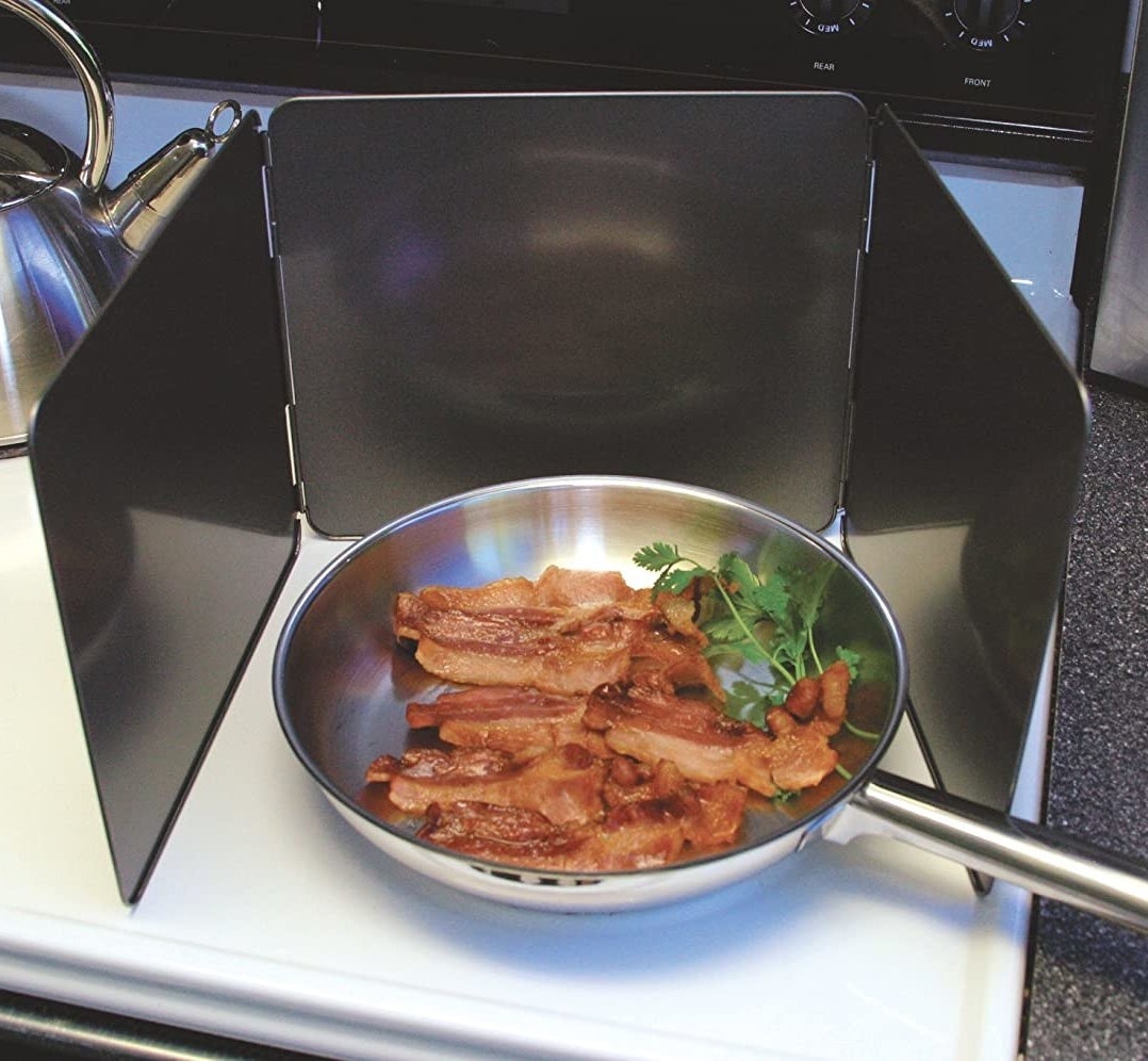 A pan of bacon surrounded by the splatter guard