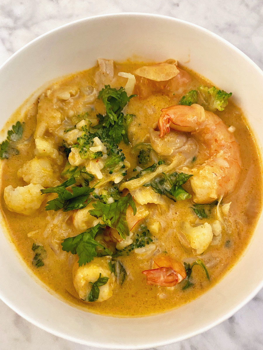 A bowl of the coconut mango curry with shrimp, broccoli, and cauliflower over rice.
