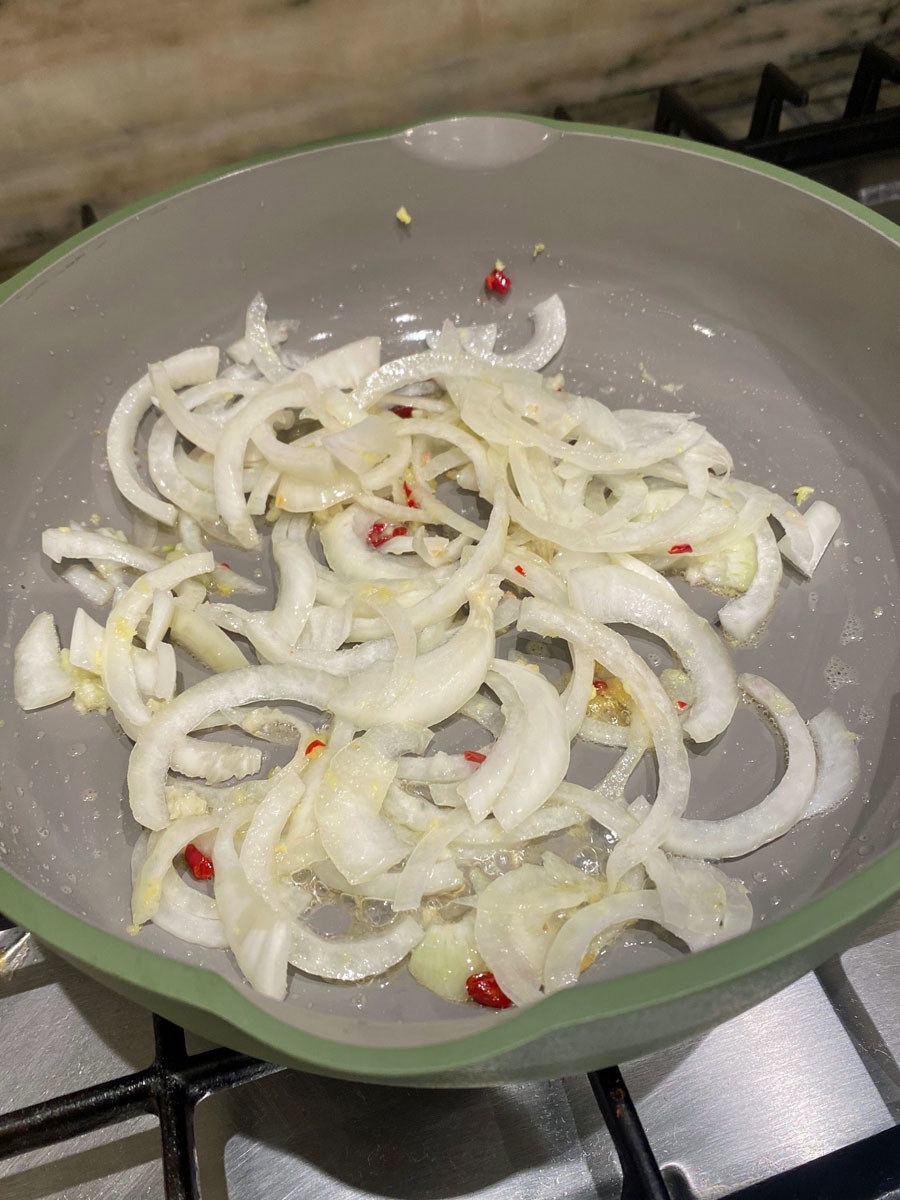 Onions, ginger, and Thai chili sautéing in a non-stick skillet.