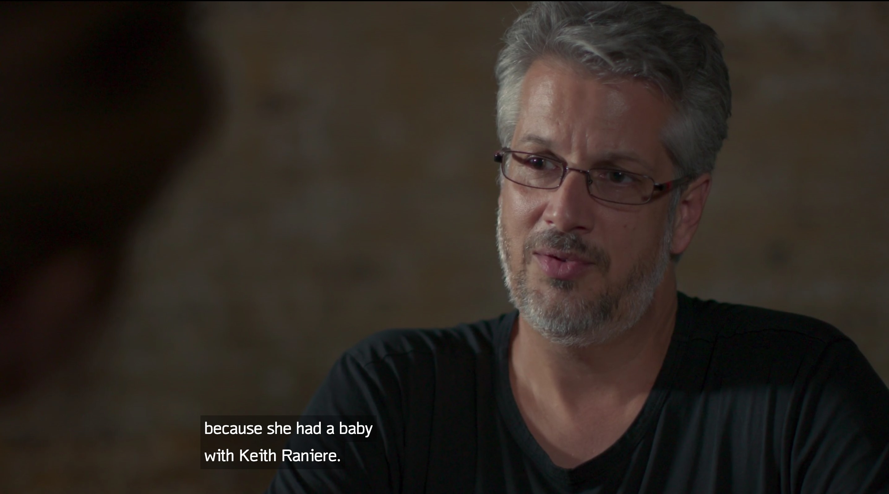 A man being interviewed with the caption text &quot;because she had a baby with Keith Raniere&quot;
