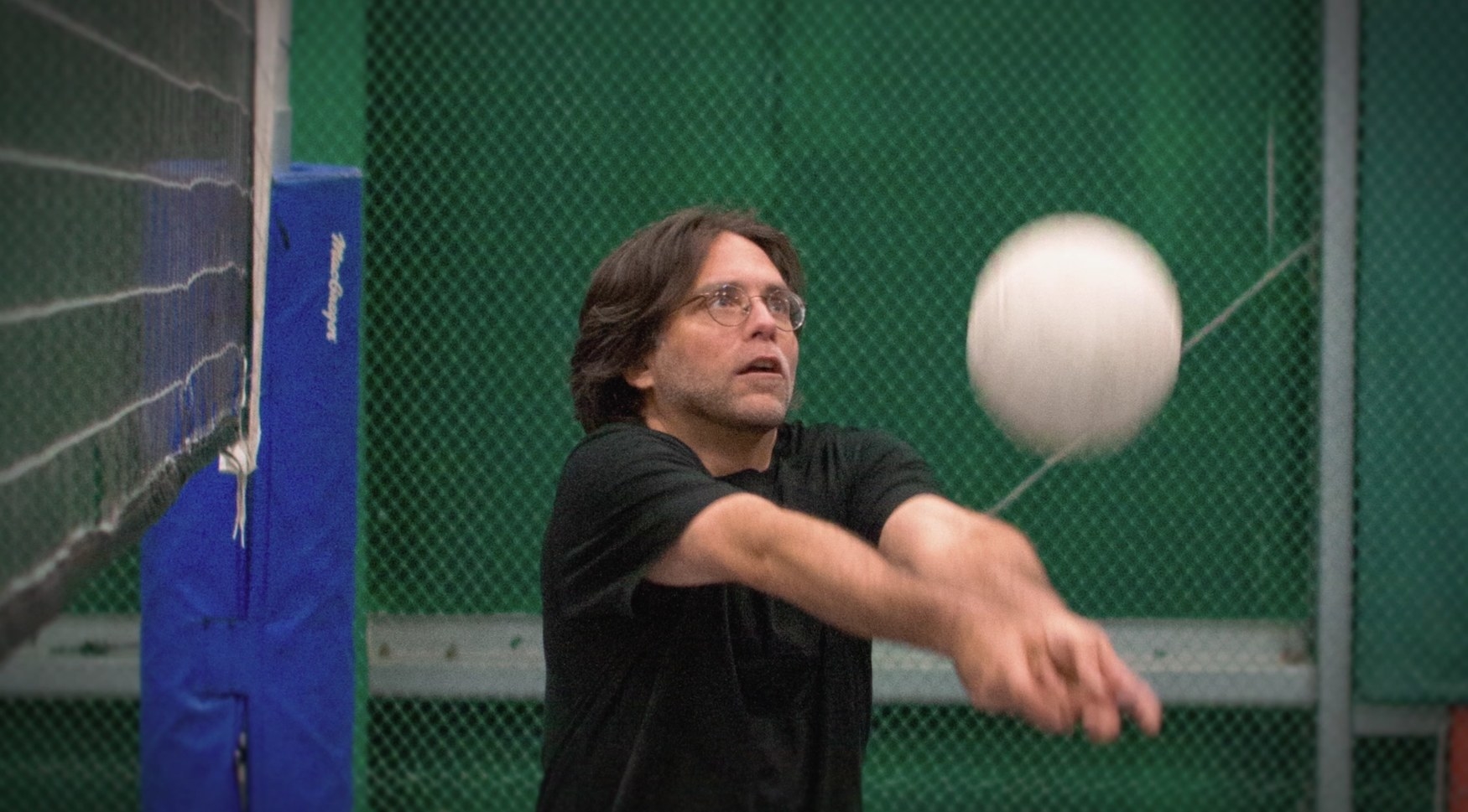 A man in glasses hitting a volleyball