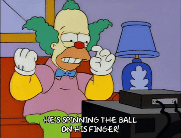 Krusty the clown in the simpsons looks at the tv and gestures emphatically whilst saying he&#x27;s spinning the ball on his finger 