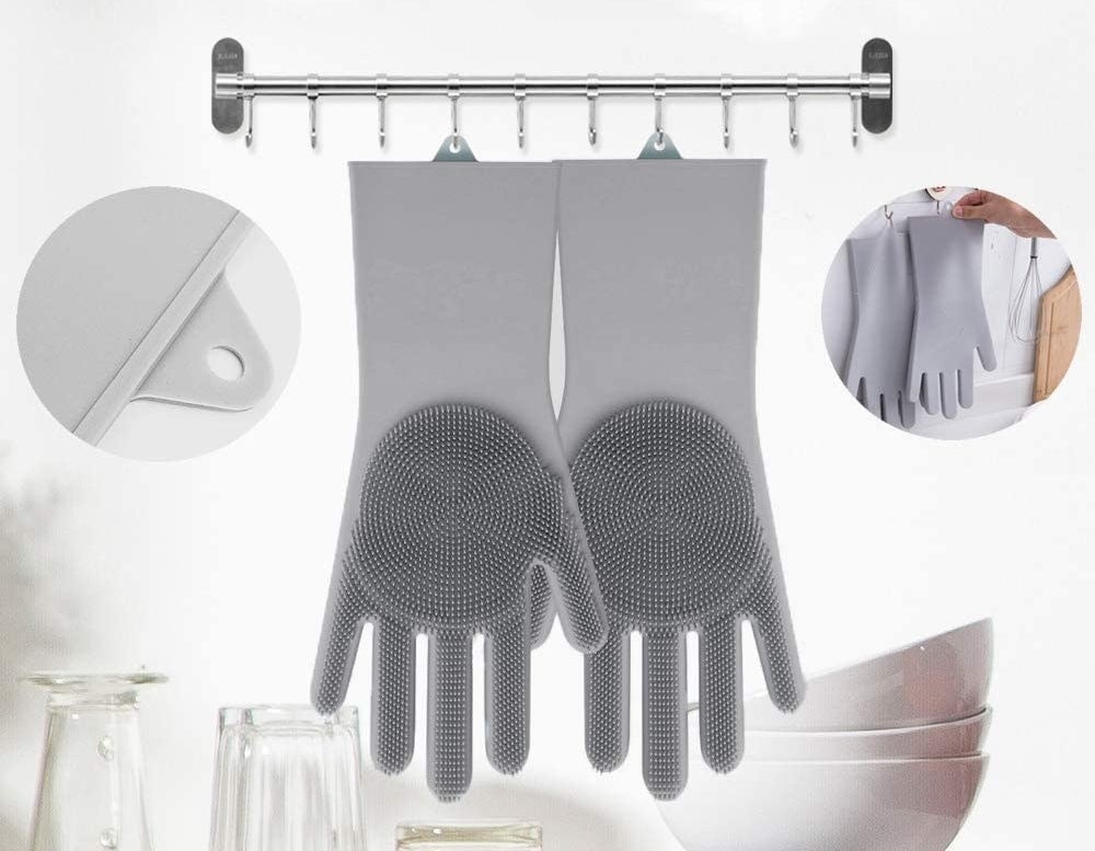A pair of silicone gloves with bristles on the palms hanging from a couple of hooks
