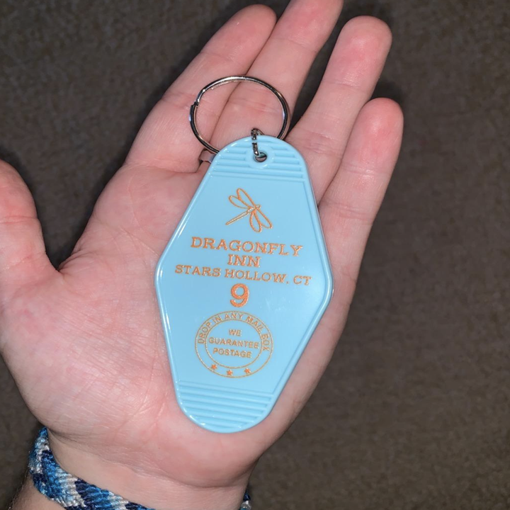 reviewer holding palm-sized Dragonfly Inn keychain 
