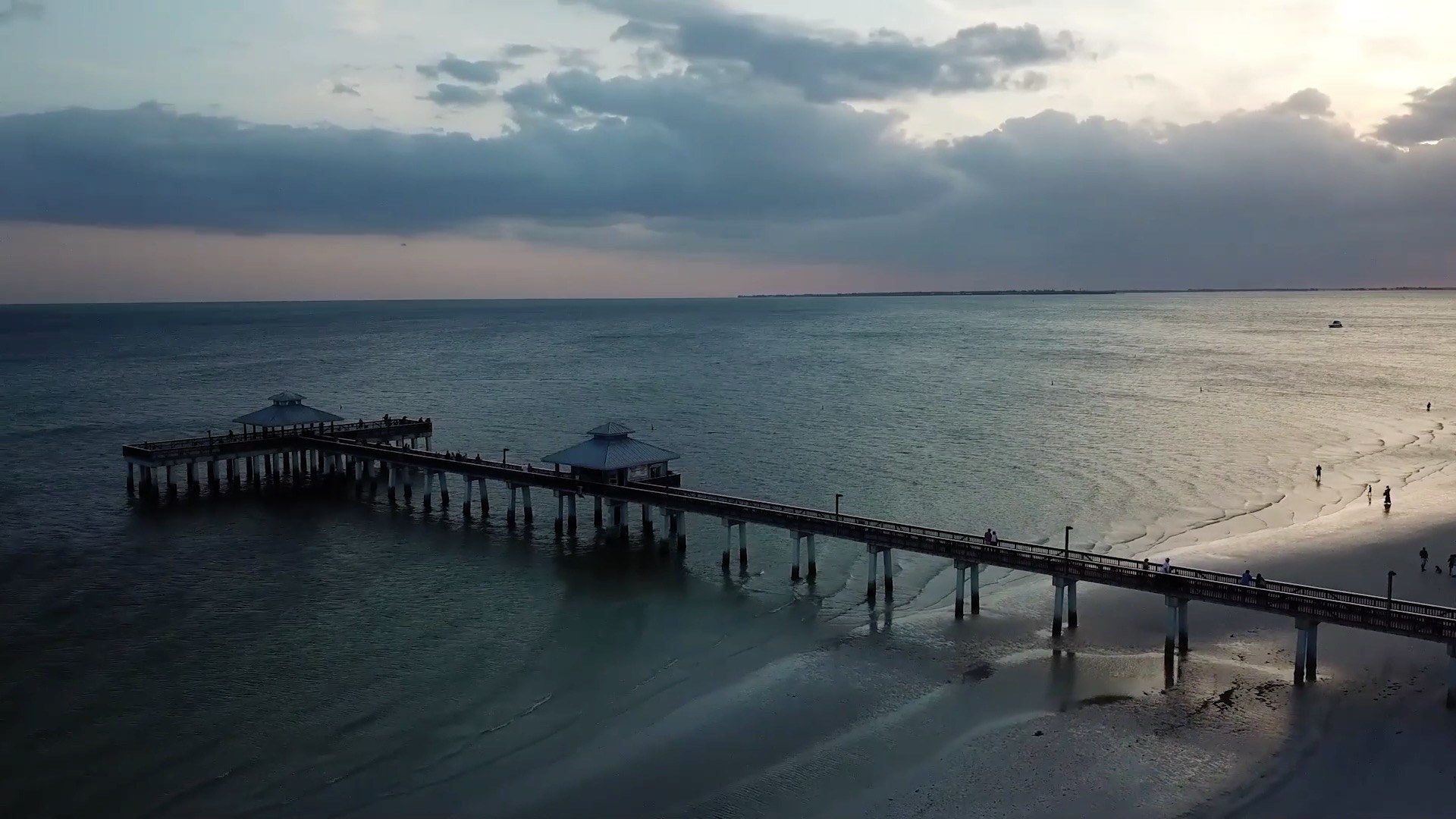 An aerial shot of a pier and a boardwalk leading into the sea